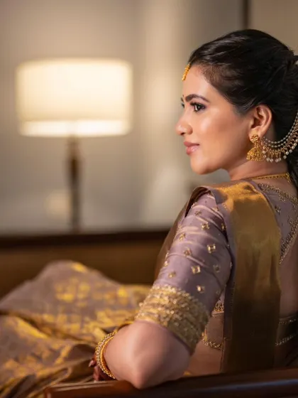 A side profile of a classic South Indian look, featuring a beautiful saree and traditional gold jewelry.