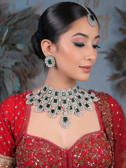 A close-up of the stunning diamond and emerald jewelry, complemented by soft, shimmery eye makeup and a neat bridal bun.