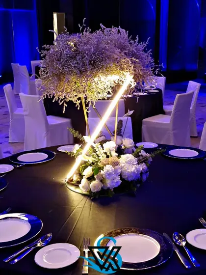 A modern tablescape featuring a striking centerpiece with integrated lighting. The black tablecloths and blue-and-white plates complete the sophisticated black, white, and blue theme.