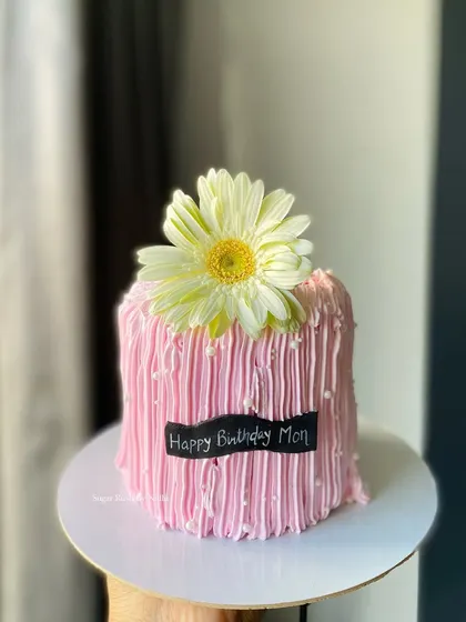 Another look at this pretty pink cake for mom. The vertical lines in the frosting create a unique texture that contrasts beautifully with the fresh flower on top.