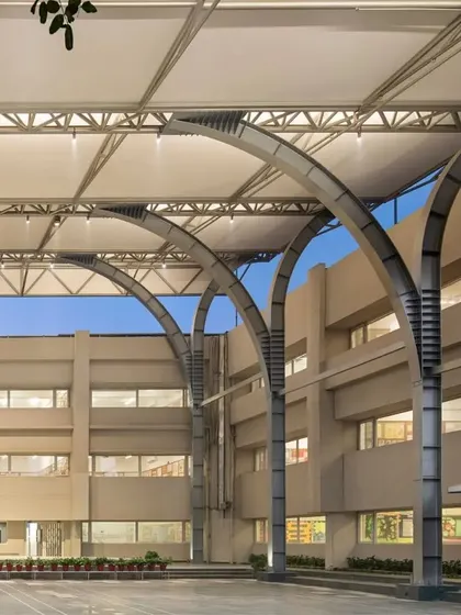 The redesigned assembly area fosters a sense of community by providing a flexible and sheltered space for large gatherings, seamlessly integrated with the school's existing architecture.