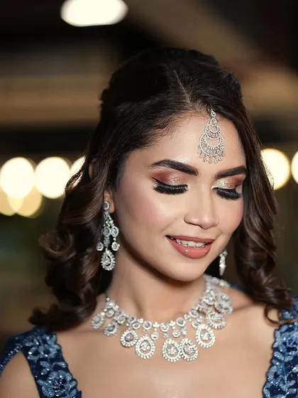 A beautiful Sangeet look with glittering bronze eyeshadow and a flawless, dewy base. The soft curls and diamond jewelry complete this glamorous party style.