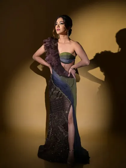 A full-length portrait of actress Ridhima Pandit in an Anjum Qureshi Label gown. The dramatic lighting highlights the unique silhouette and the beautiful color gradient of the fabric.