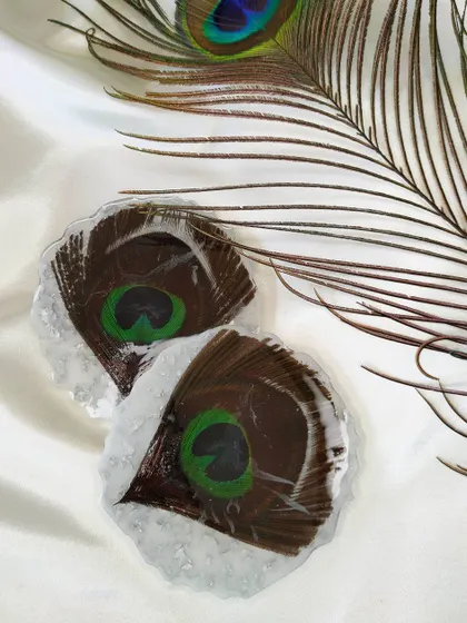 A pair of my peacock feather coasters. Each one is unique, capturing the iridescent beauty and intricate patterns of the feather.