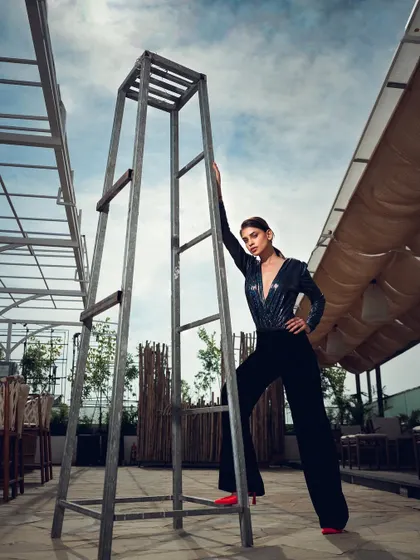 A powerful pose in an industrial-style outdoor setting. The strong lines of the ladder and the model's pose create a visually compelling, high-fashion image.