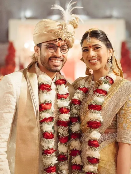 A classic portrait of the newly married couple, smiling and adorned with their varmalas.