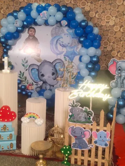 An elephant-themed birthday setup with a neon "Happy Birthday" sign and character cutouts.