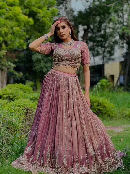 A full-length shot of a model wearing a dusty rose lehenga with delicate silver embroidery, perfect for an elegant and understated look.