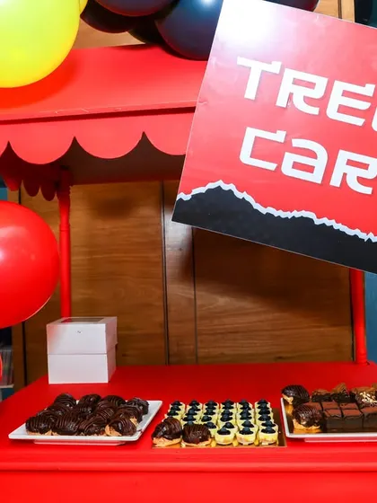 A bold red 'Treat Cart' for a Deadpool-themed party, serving a selection of delicious chocolate desserts.