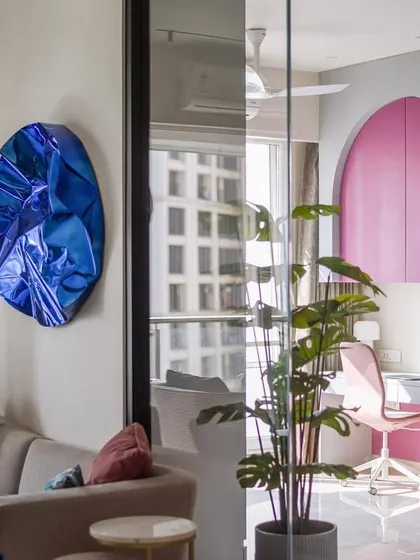 This guest room doubles as a home office thanks to a glass partition. The playful pink arched desk area can be opened up to the living room, showcasing how flexible design can add value and optimize the potential of a space.