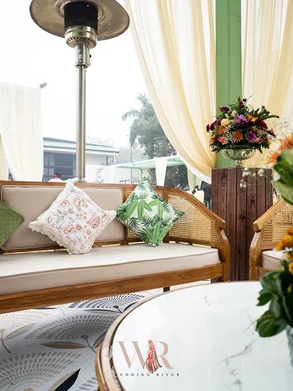 Another view of the cane furniture lounge, highlighting the printed cushions and the lush, natural setting. The design prioritizes comfort without sacrificing style.