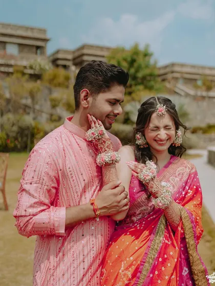 A playful and candid moment where the bride is applying Haldi to the groom's cheek, both sharing a laugh.