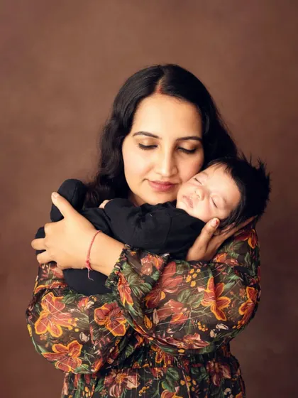 The warmth of a mother's embrace. The rich brown background and her floral dress add a beautiful, warm tone to this loving portrait.