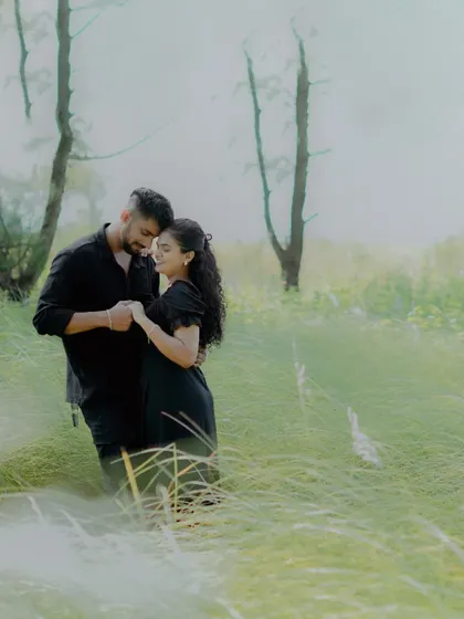 A dreamy and hazy pre-wedding photo of a couple in a field of tall grass, creating a soft and romantic mood.