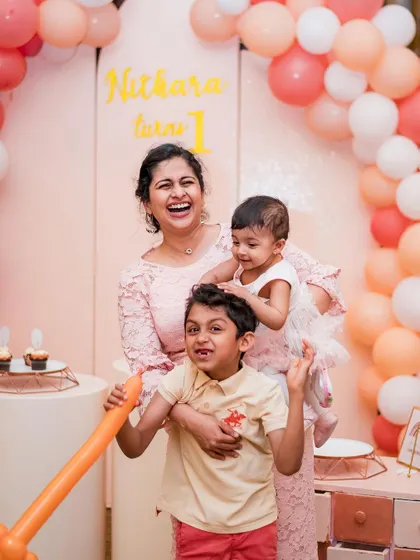 A mother shares a laugh with her children at a first birthday party, a perfect example of the candid family joy we aim to capture.