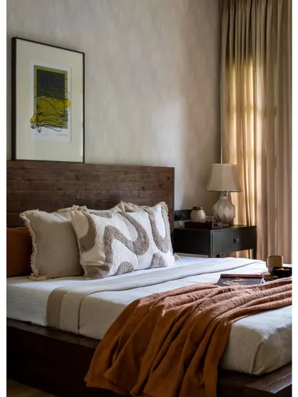 A feature image of the rustic modern bedroom, focusing on the textural details of the bedding and the dark wood headboard. The warm throw and patterned pillows add a touch of bohemian soul.