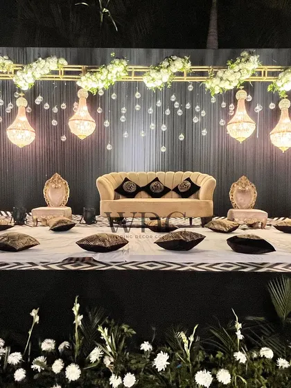 A unique low-seating arrangement on the stage, with a backdrop of hanging crystal chandeliers, offering a modern and relaxed alternative to a traditional sofa.