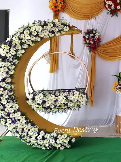 A close-up of my popular crescent-moon cradle design. I cover the entire structure with fresh white daisies and other flowers, making it a stunning centerpiece for any naming ceremony or baby shower.