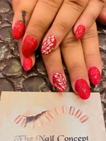 A simple and elegant set of bright red almond nails. The ring fingers are accented with a delicate, hand-painted white leaf pattern.