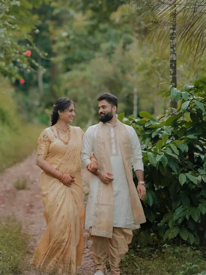 The couple walks hand in hand through a natural path, sharing a look of love and companionship.