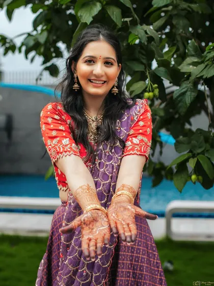 A joyful shot showing off her henna. The makeup is fresh and minimal, allowing her natural happiness and the bright colours of her outfit to be the focus.