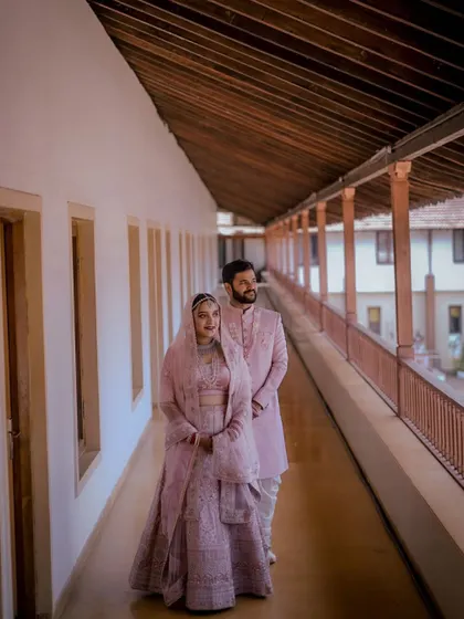 A full-length portrait of the couple in a long corridor, the repeating architectural elements creating a sense of depth and grandeur.