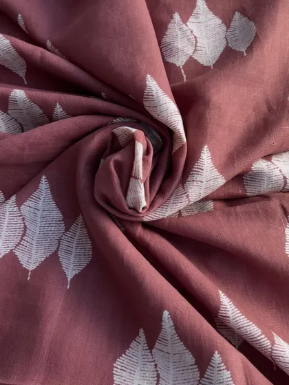A close-up of our printed pure linen in a mauve shade, showcasing the delicate white leaf print and the beautiful texture of the fabric.