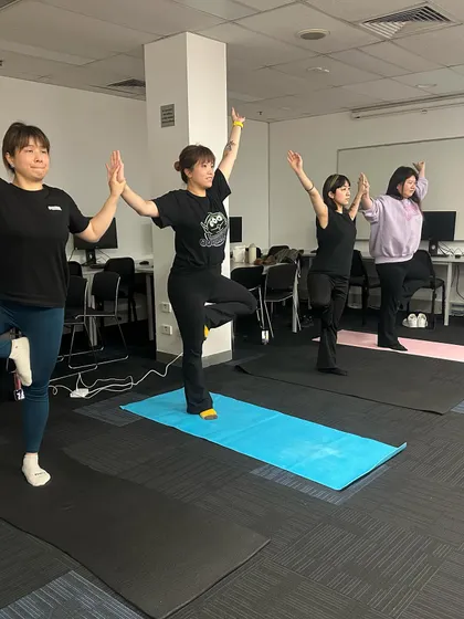 Students holding hands for support in tree pose. This demonstrates the community and connection we build in my classes.