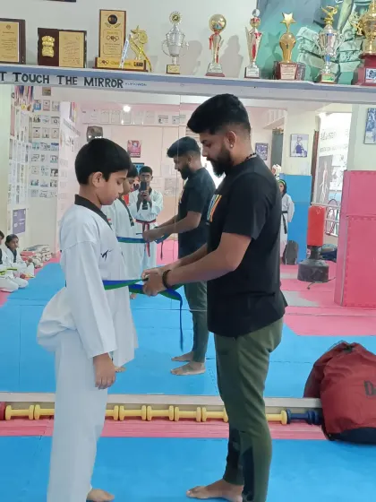 Tying a new green and blue belt for a student.
