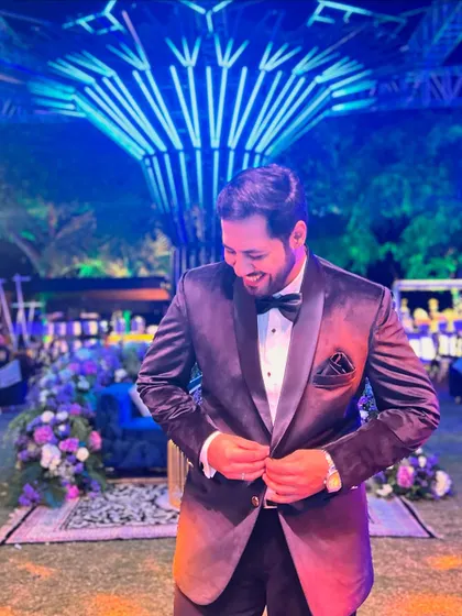 Adjusting my tuxedo, ready to get back on stage and bring more energy to the Sangeet party.