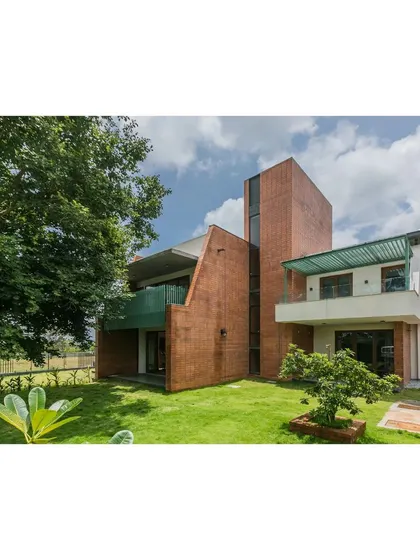 The exterior of 'An Earthy Affair' showcases a bold composition of intersecting volumes clad in exposed brick. The design responds to the local climate, with deep overhangs and shaded balconies providing relief from the sun while maintaining a strong connection to the outdoors.