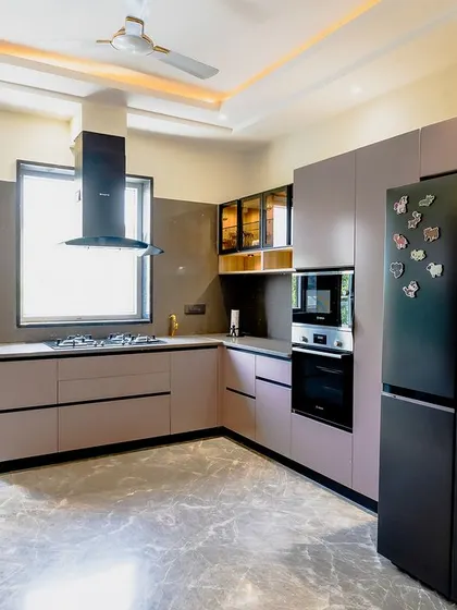 A wider view of the dusty pink kitchen, showing the L-shaped layout and the integrated appliances that make this space highly functional.