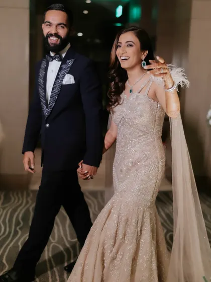 Walking into the party hand-in-hand. Her makeup is designed to look stunning in motion, capturing the fun and energy of the night.