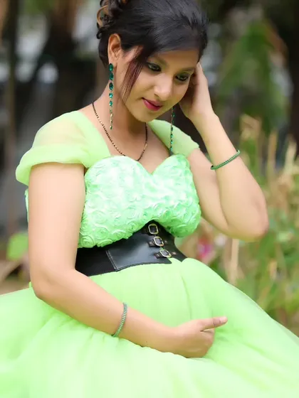 A close-up portrait of a woman in a lime green maternity gown, showing the detailed texture of the dress.