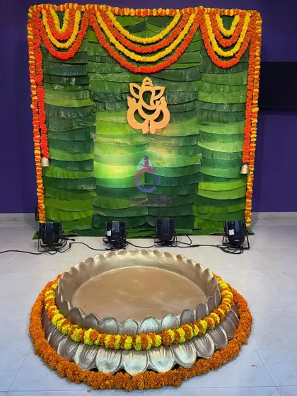 A full view of our banana leaf Haldi backdrop with a lotus-shaped brass uruli in the front, ready for the ceremony.