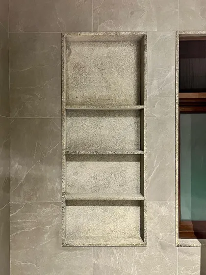 A built-in shelving niche made from textured granite provides elegant storage within the bathroom. This detail showcases our focus on integrating functional elements seamlessly into the design.