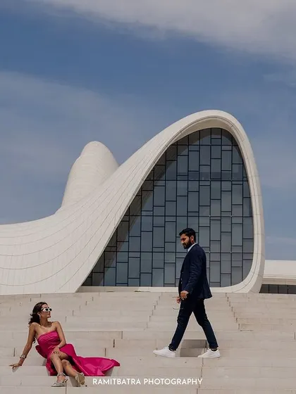 A different perspective of the couple on the steps, emphasizing the unique lines of the architecture.
