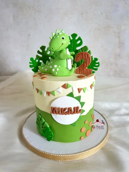 A cute green dinosaur cake with a bunting banner and leafy green details.