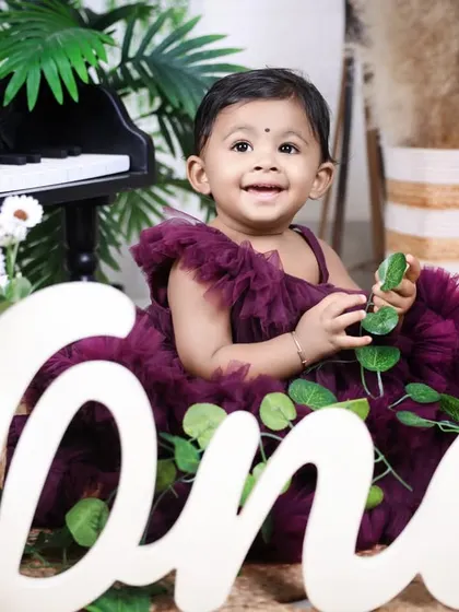 A beautiful composition featuring the birthday girl with the "one" sign and piano. The natural elements like leaves add a fresh touch to the studio setup.