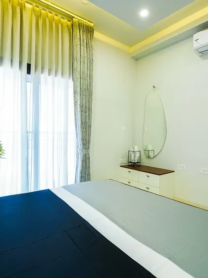 A different angle of the minimalist bedroom, showing the floating vanity table with an oval mirror, perfectly balancing modern design with inviting warmth.