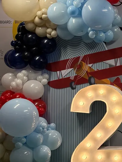 A close-up of the airplane-themed decor, showing the marquee number '2' next to a classic red, white, and blue balloon arch.