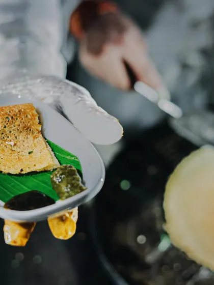 A mini dosa, perfectly crisp and golden, served fresh off the griddle. Paired with traditional chutneys on a banana leaf, it's a taste of South India that's always a crowd-pleaser at my events.
