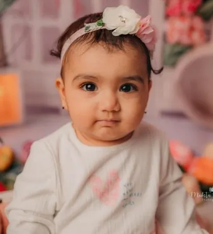 This 8-month-old beauty is looking right at the camera, ready for her close-up in a garden of flowers.