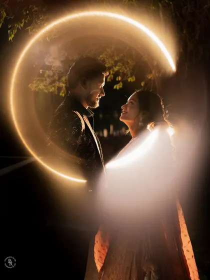 A creative light painting portrait of a couple, with a crescent of light encircling them in the dark, creating a magical effect.