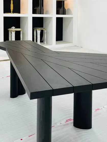 This funky, geometric table is a harmonious blend of aesthetics and purpose. Crafted from solid wood with a black finish, its unique planked top and cylindrical legs make it a statement piece for any modern interior.