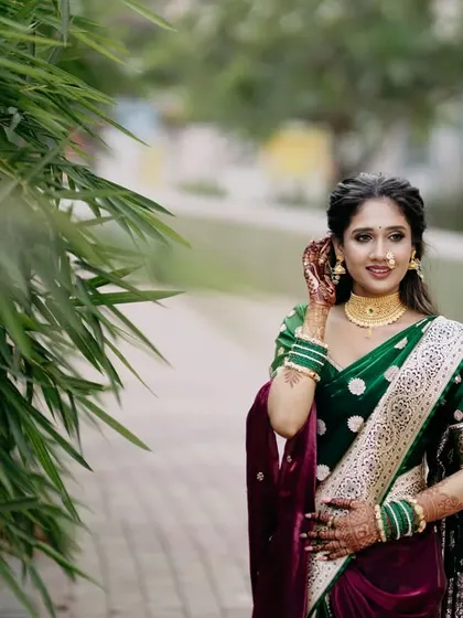 A candid shot of the bride walking and adjusting her nath, a classic Maharashtrian nose ring. Her natural grace and the beauty of her traditional attire shine in this lovely outdoor portrait.