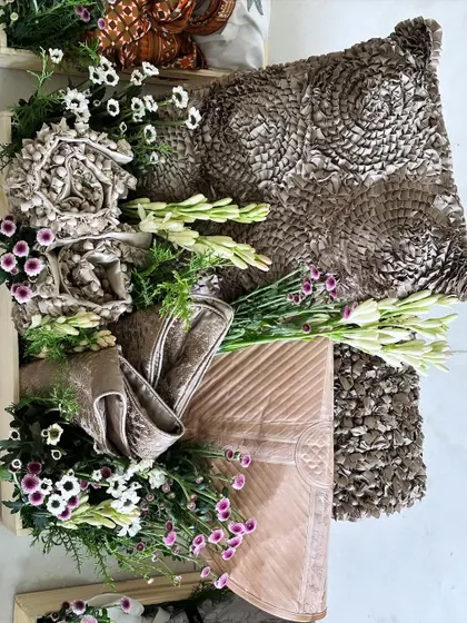 A unique trousseau piece featuring a textured brown cushion and matching fabric, beautifully arranged with fresh white tuberoses.