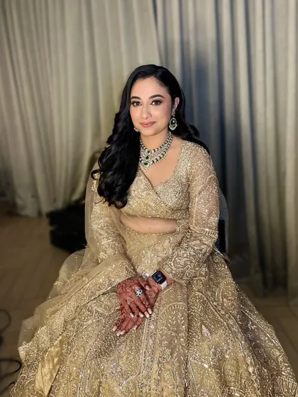 Neha, stunning in her full reception attire. The makeup is elegant and polished, designed to complement her heavily embroidered golden lehenga.