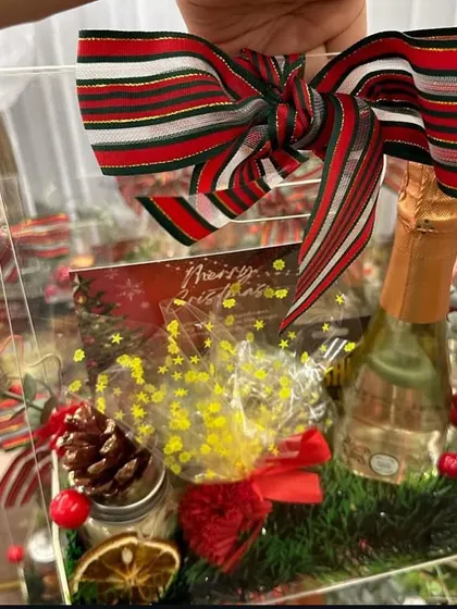 We also create beautiful Christmas hampers, like this one featuring a bottle of sparkling wine, festive treats, and decorations, all in a clear acrylic box.