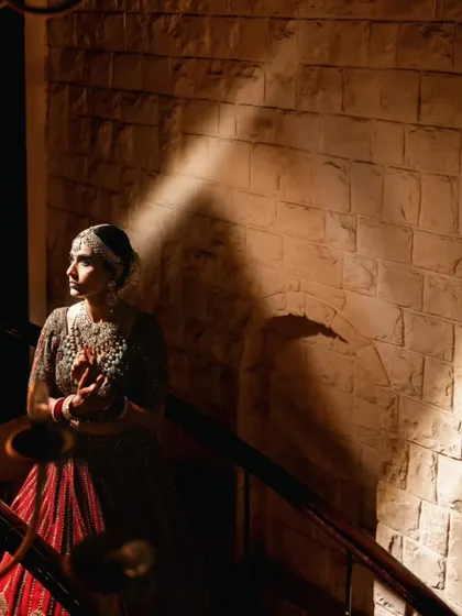 A creative bridal portrait using a sliver of light to highlight the bride's profile against a textured wall, creating a sense of mystery and elegance.